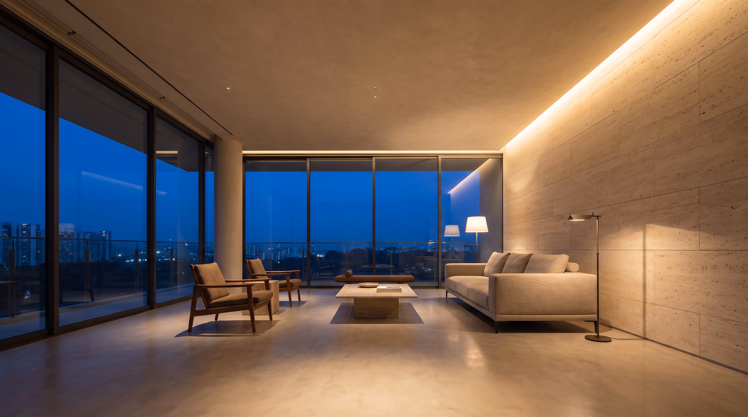 Living room at dusk lit by warm cove lighting and wall grazing, with the dusk sky through full-height glazing