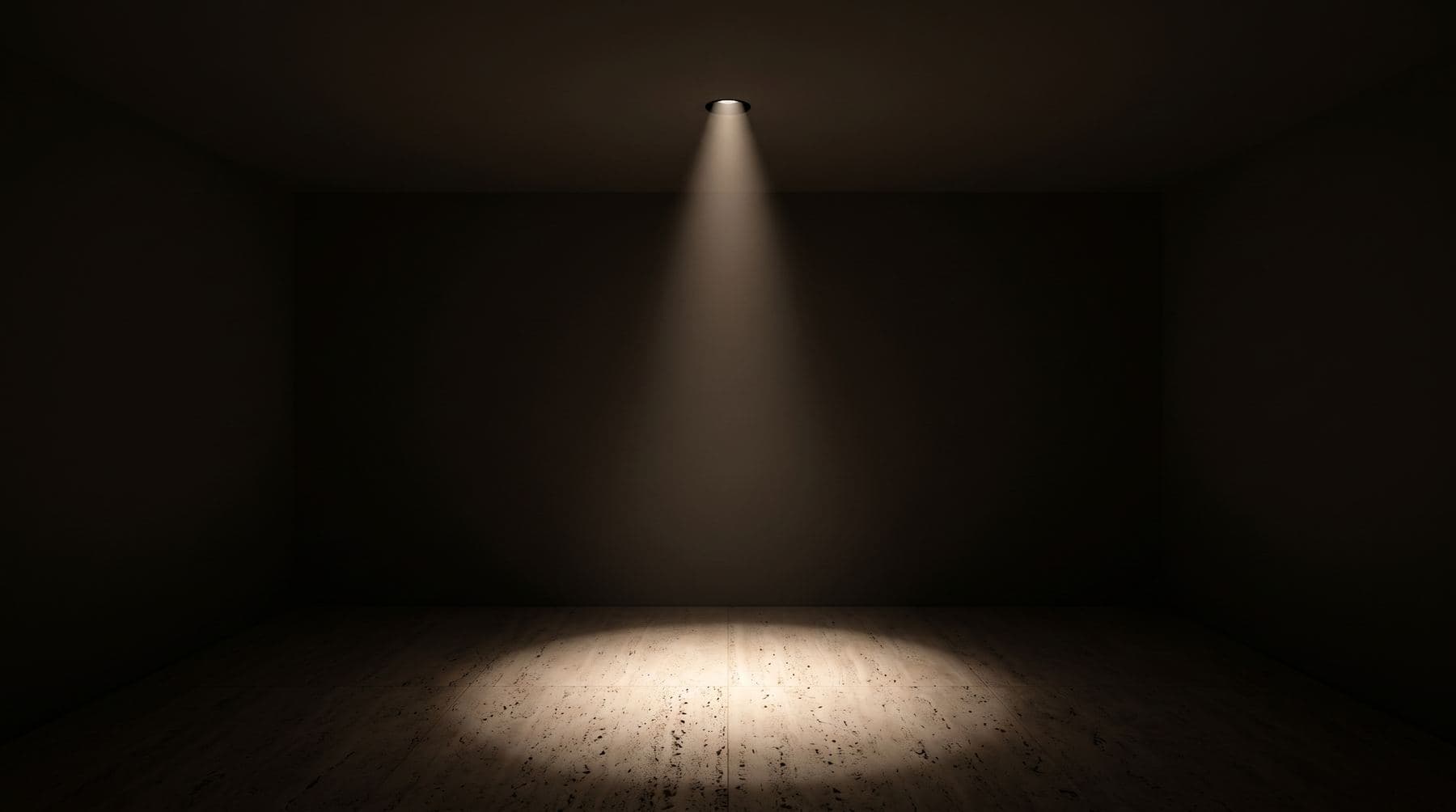A single recessed downlight casting a soft cone of light onto a travertine floor in a dark room