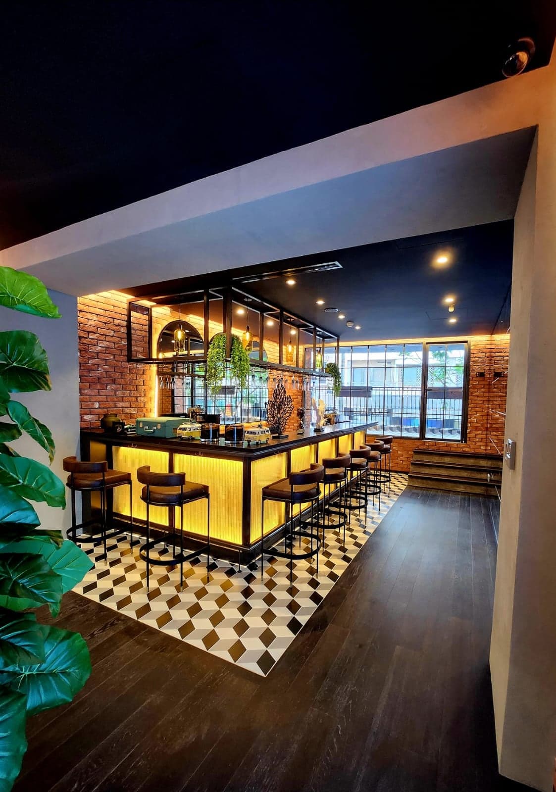 Boutique bar with a backlit amber front, brick walls washed with concealed light and a patterned tile floor